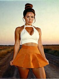 A sultry athletic woman in 70s style poses on a dusty rural road at sunset