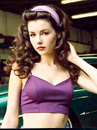 Lady emerges in the dimly lit auto repair shop 1950s era style surrounding her slender frame