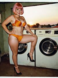 A 26 year old woman in orange bikini and C cup breasts lounges in laundry room